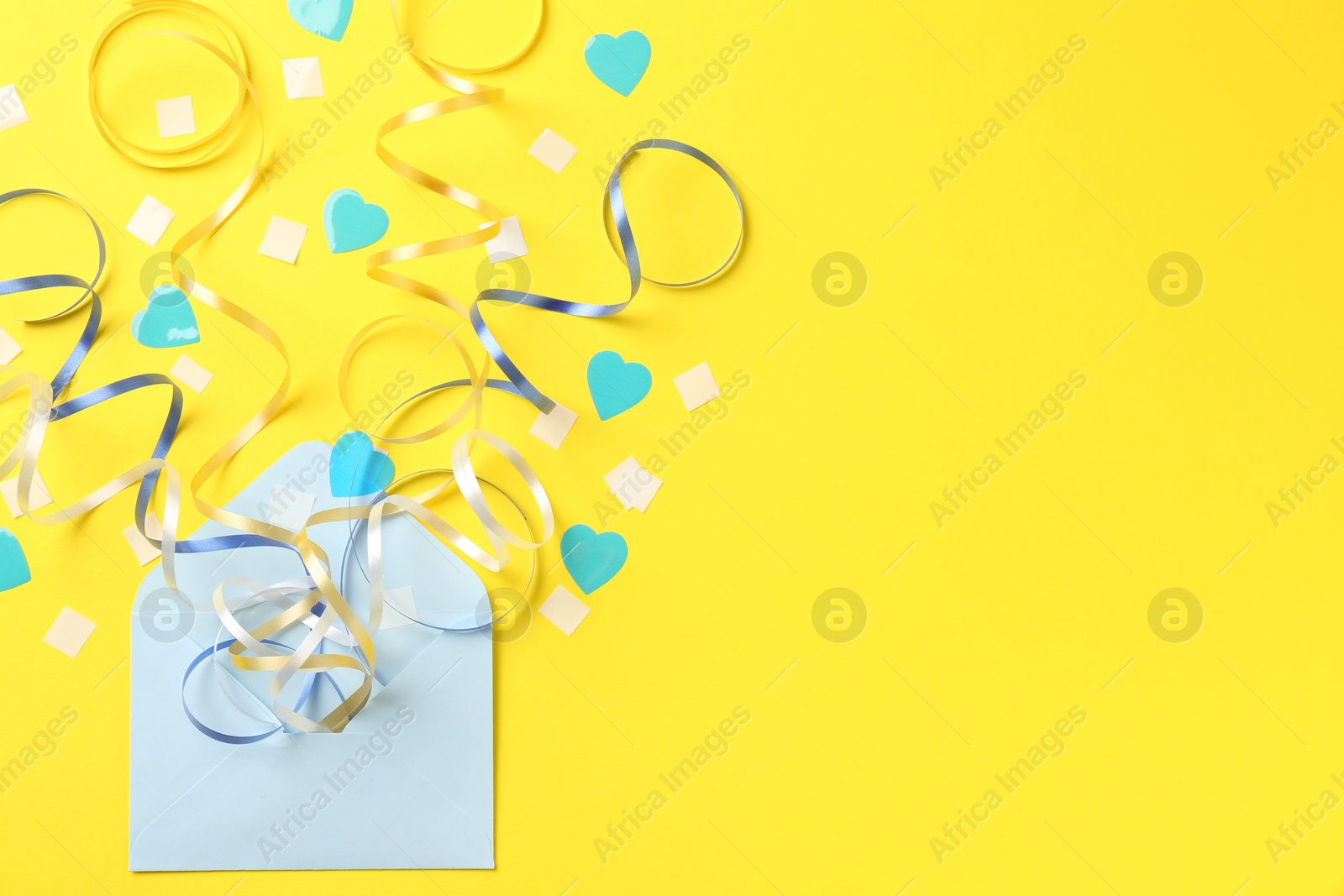 Photo of Envelope with confetti and party streamers on yellow background, flat lay. Space for text