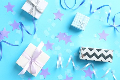 Photo of Confetti, party streamers and gift boxes on light blue background, flat lay