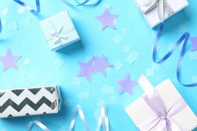 Confetti, party streamers and gift boxes on light blue background, flat lay