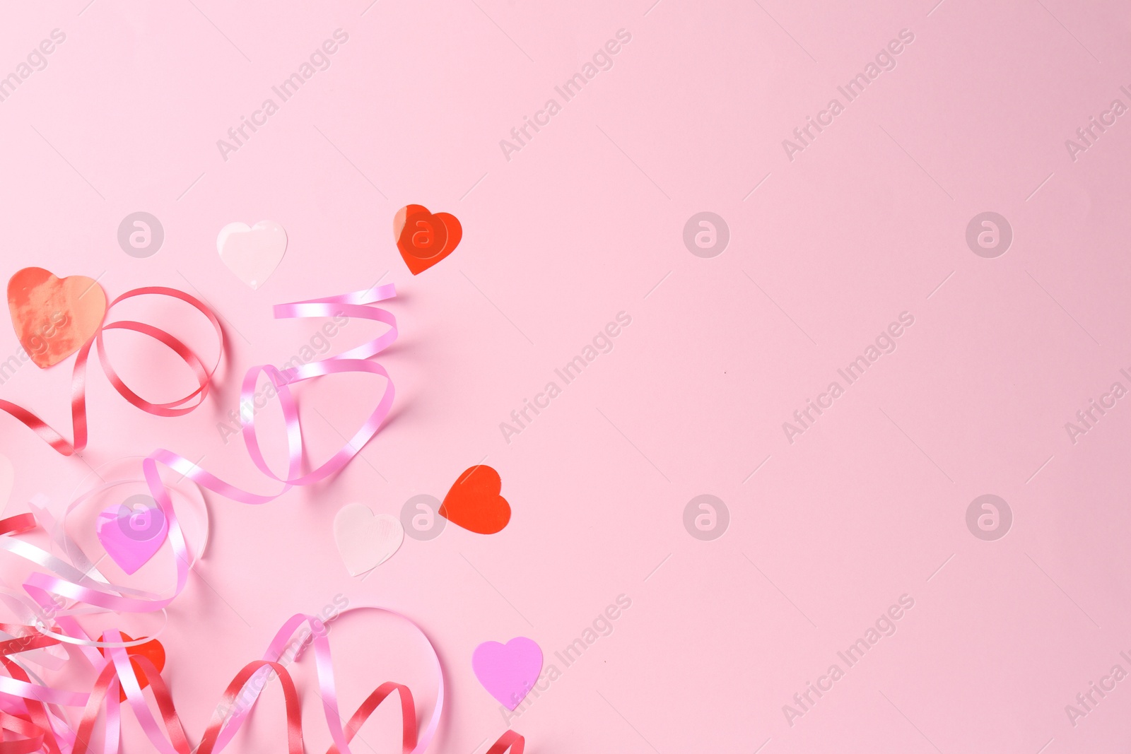 Photo of Confetti and party streamers on pink background, flat lay. Space for text