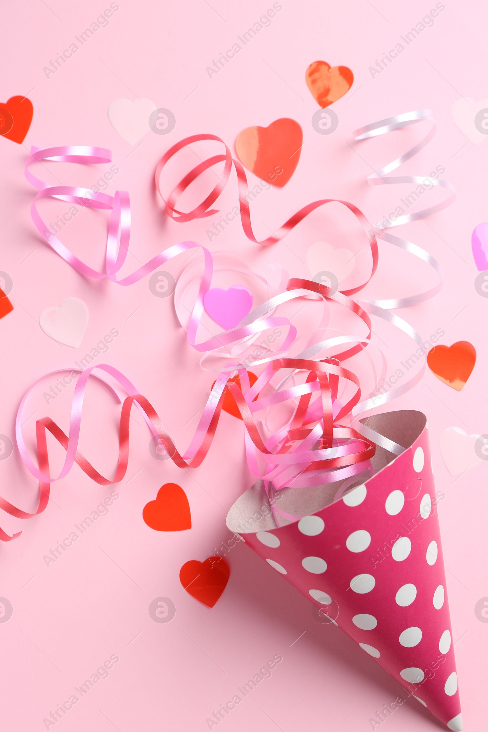 Photo of Party hat with confetti and streamers on pink background, flat lay