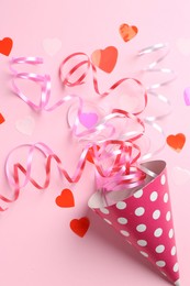 Photo of Party hat with confetti and streamers on pink background, flat lay