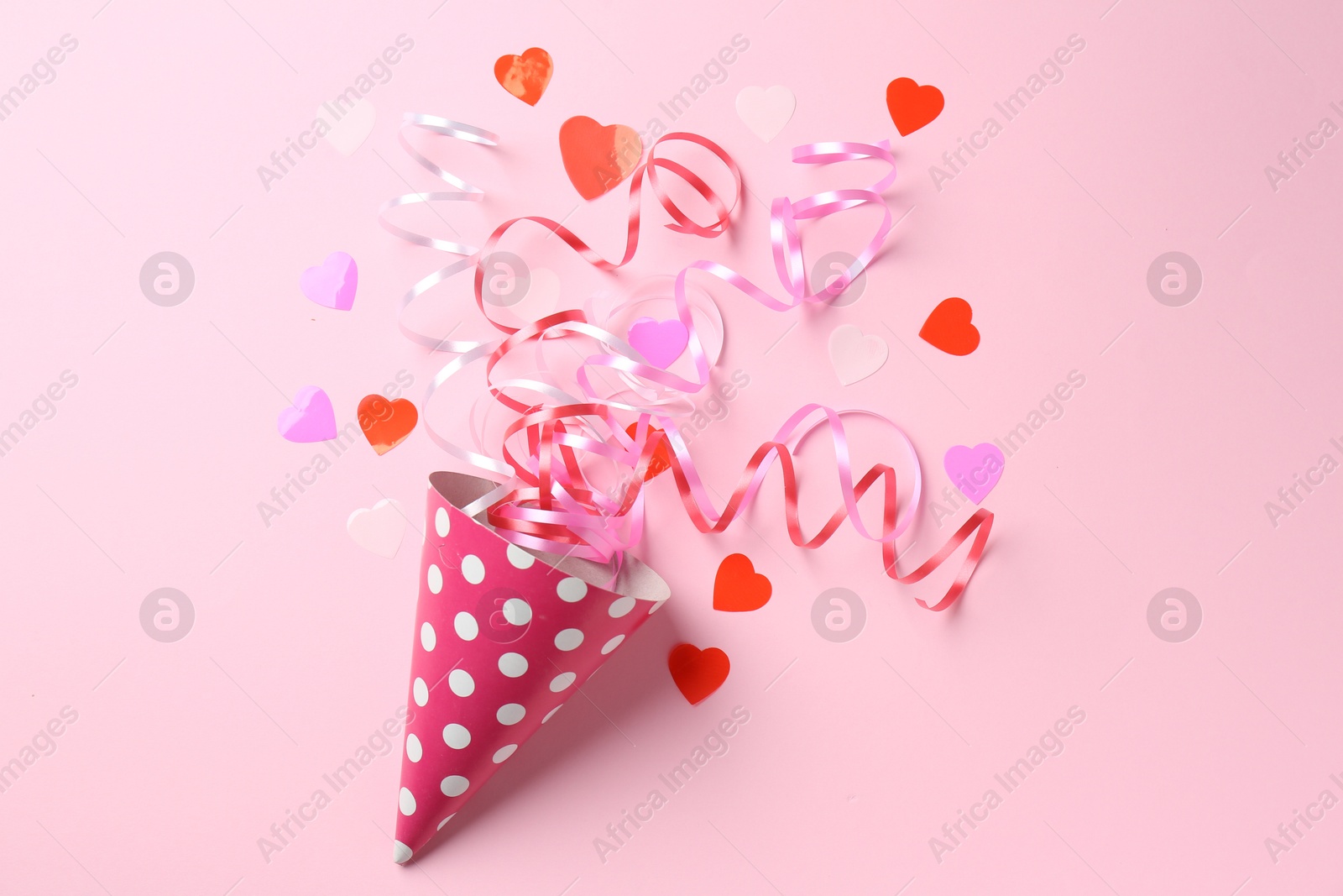 Photo of Party hat with confetti and streamers on pink background, flat lay