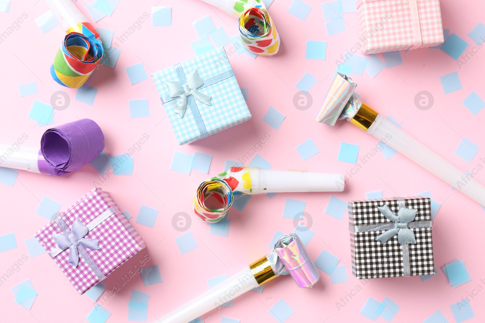 Photo of Confetti, gift boxes and party horns on pink background, flat lay