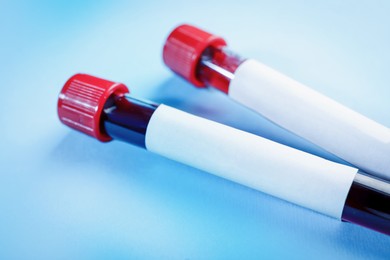 Image of Blood in test tubes with blank labels on light blue background, closeup. Laboratory analysis