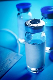 Image of Medication in glass vials with blank labels on light blue background, closeup