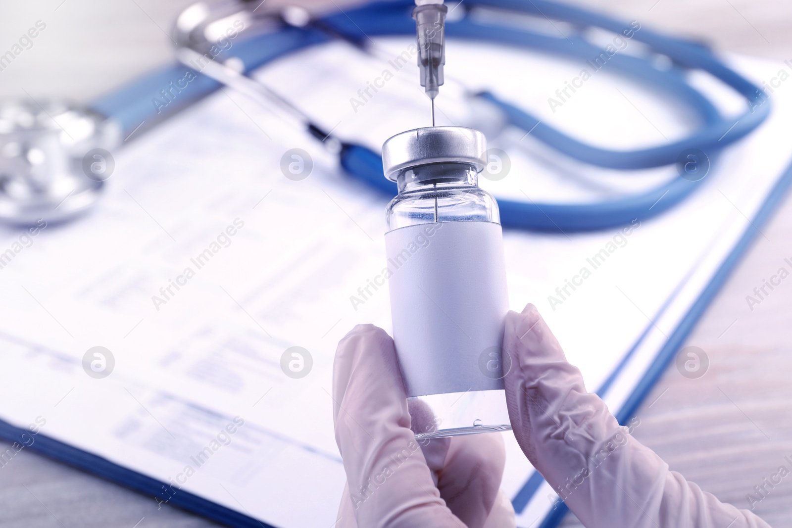 Image of Nurse filling syringe with medication from vial over table, closeup. Space for text