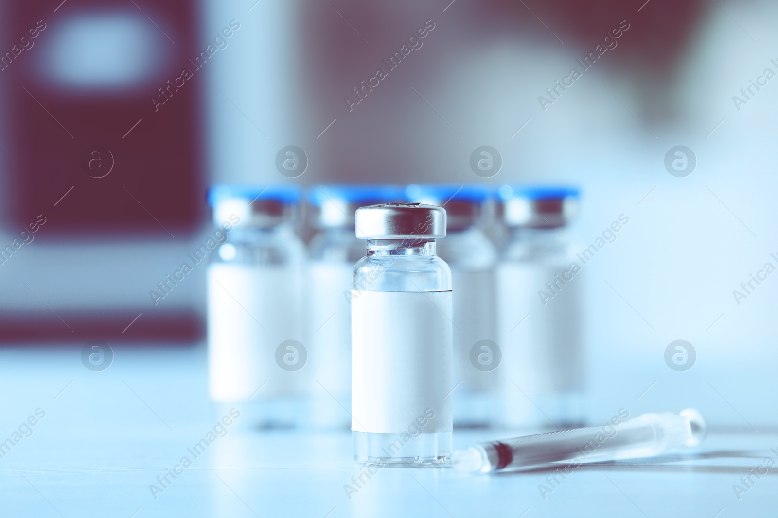 Image of Medication in vials with blank labels and syringe on white table