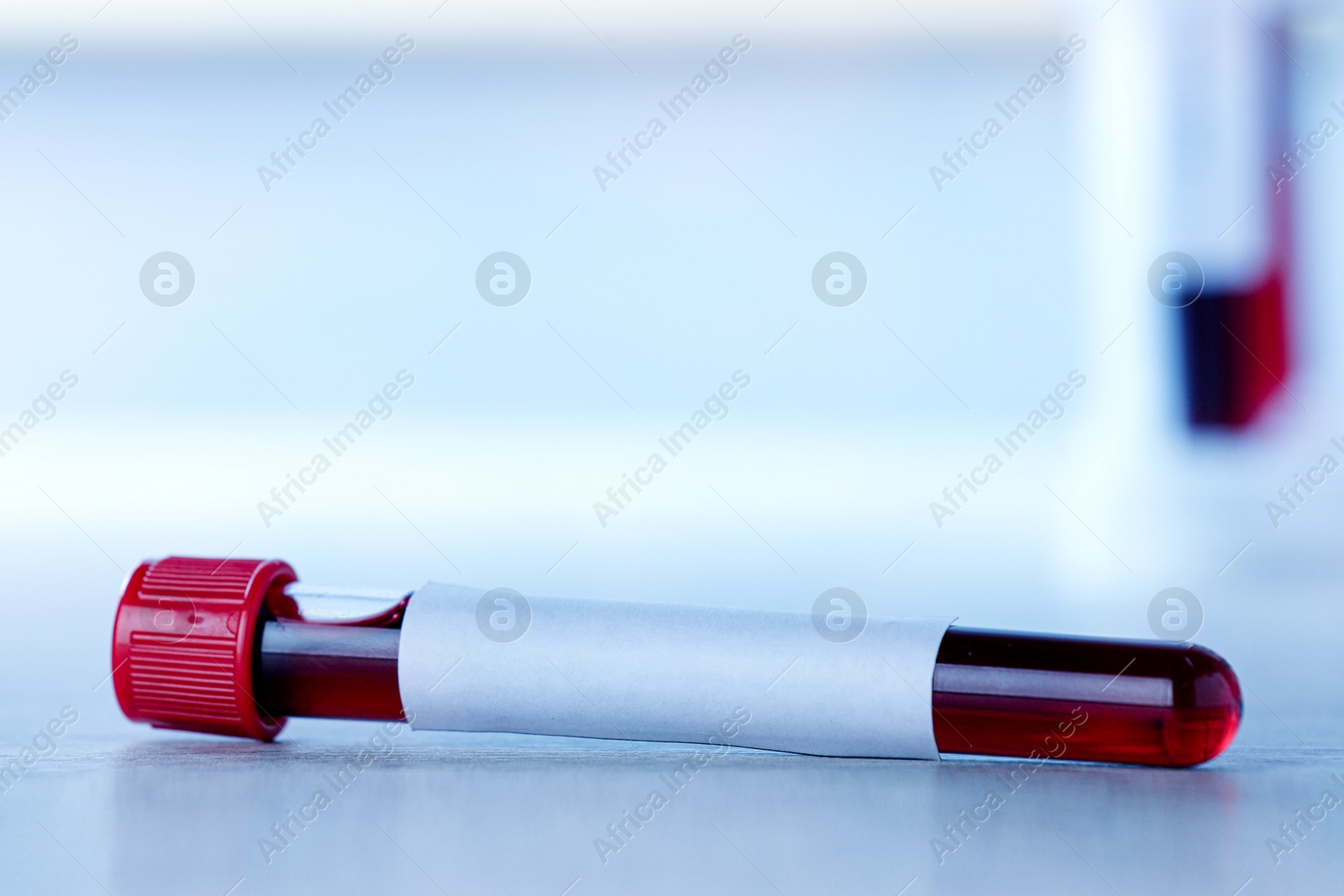 Image of Blood in test tube with blank label on table, closeup. Medical analysis