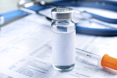 Medication in vial with blank label and syringe on medical form, closeup