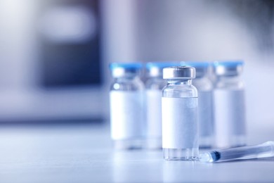 Medication in vials and syringe on white table, space for text