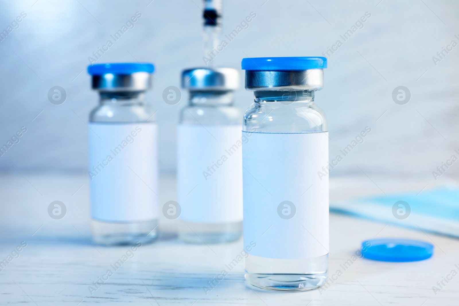 Image of Medication in glass vials on white wooden table, closeup