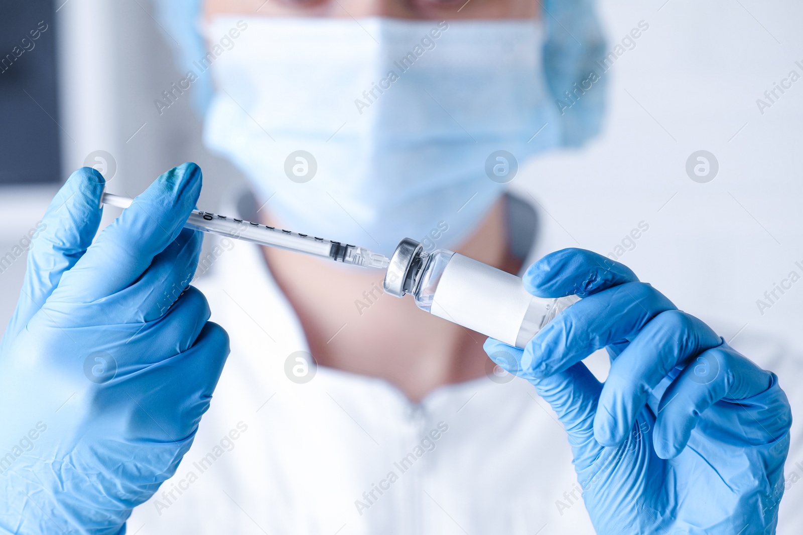 Image of Nurse filling syringe with medication from glass vial in hospital, closeup