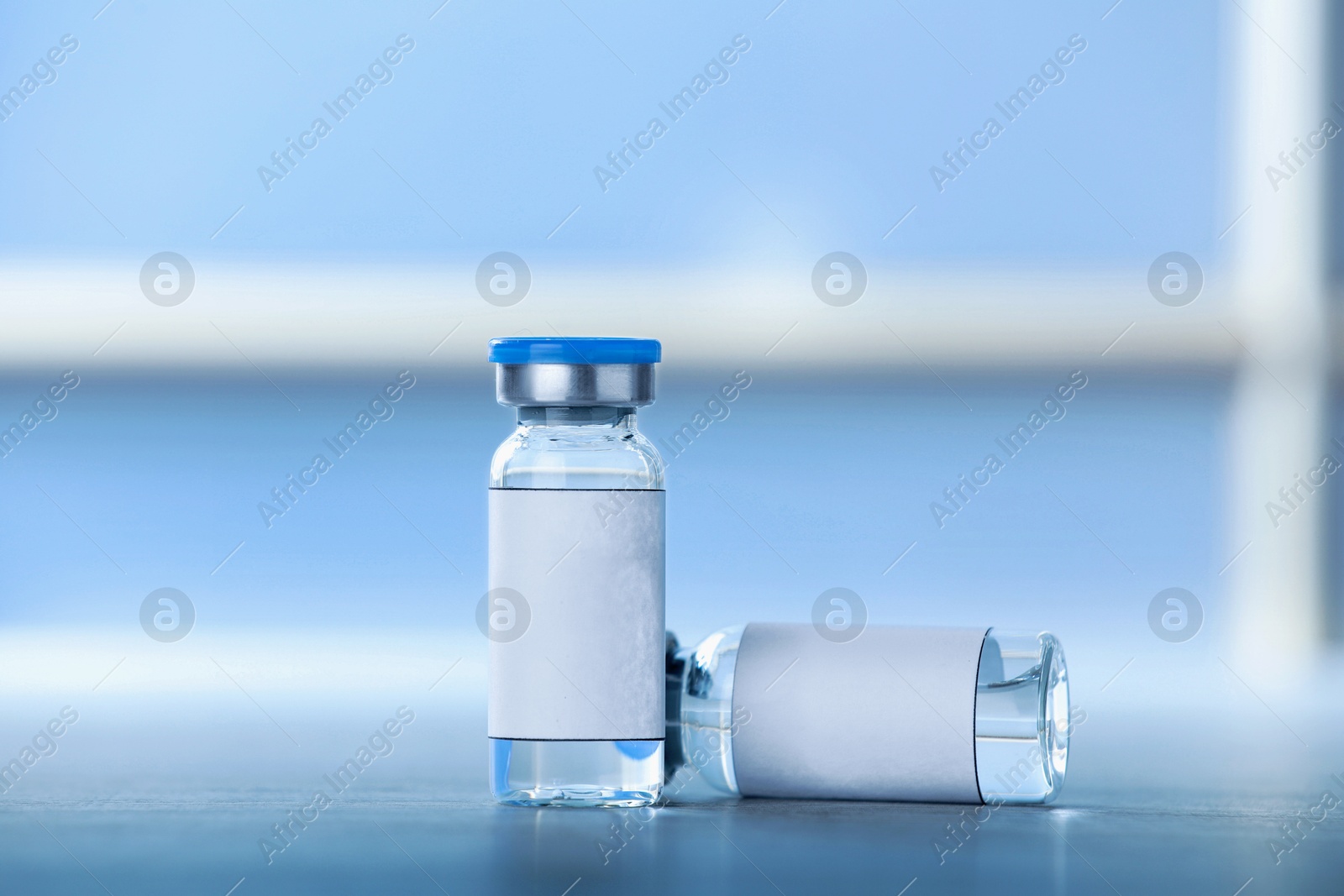 Image of Medication in glass vials with blank labels on table, space for text