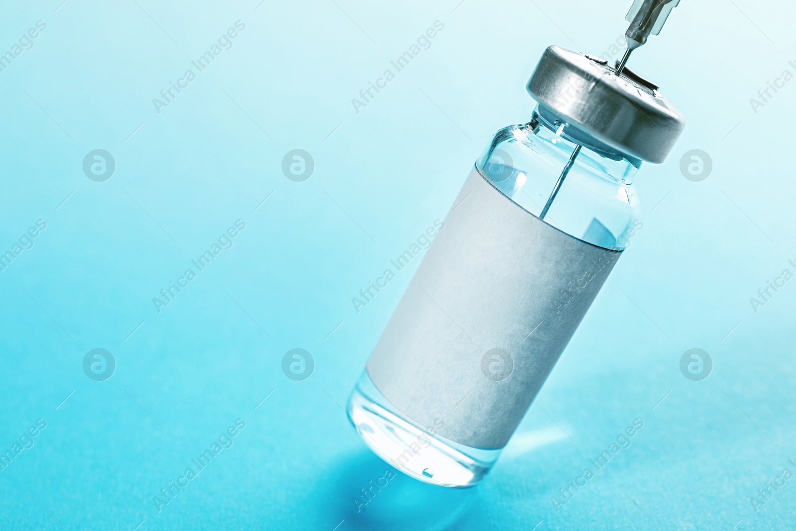 Image of Filling syringe with medication from vial on turquoise background, closeup. Space for text