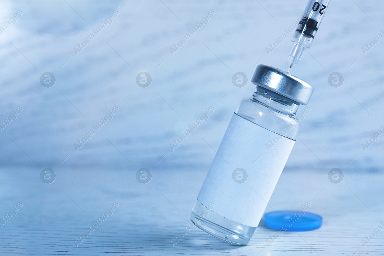 Image of Filling syringe with medication from vial at white wooden table, closeup. Space for text