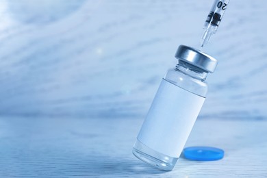 Filling syringe with medication from vial at white wooden table, closeup. Space for text