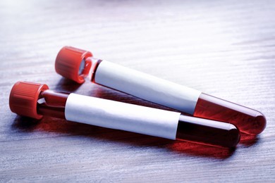 Blood in test tubes with blank labels on wooden table, closeup. Laboratory analysis