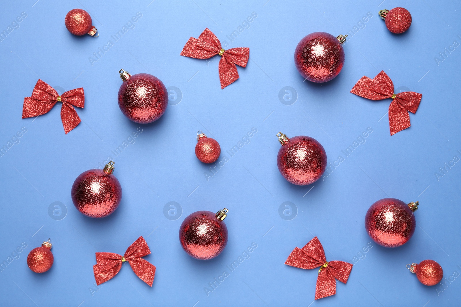 Photo of Christmas balls and bows on blue background, flat lay