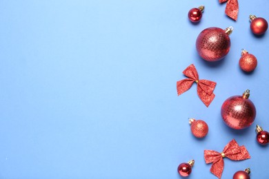 Photo of Christmas balls and bows on light blue background, flat lay. Space for text