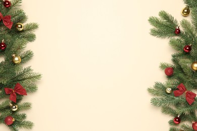 Photo of Fir tree branches with bows and Christmas balls on beige background, flat lay. Space for text