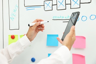 Developing UI design. Woman drawing website wireframe on whiteboard indoors, closeup