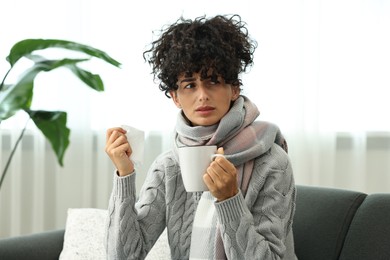 Cold symptom. Young woman with tissue and cup of hot drink at home