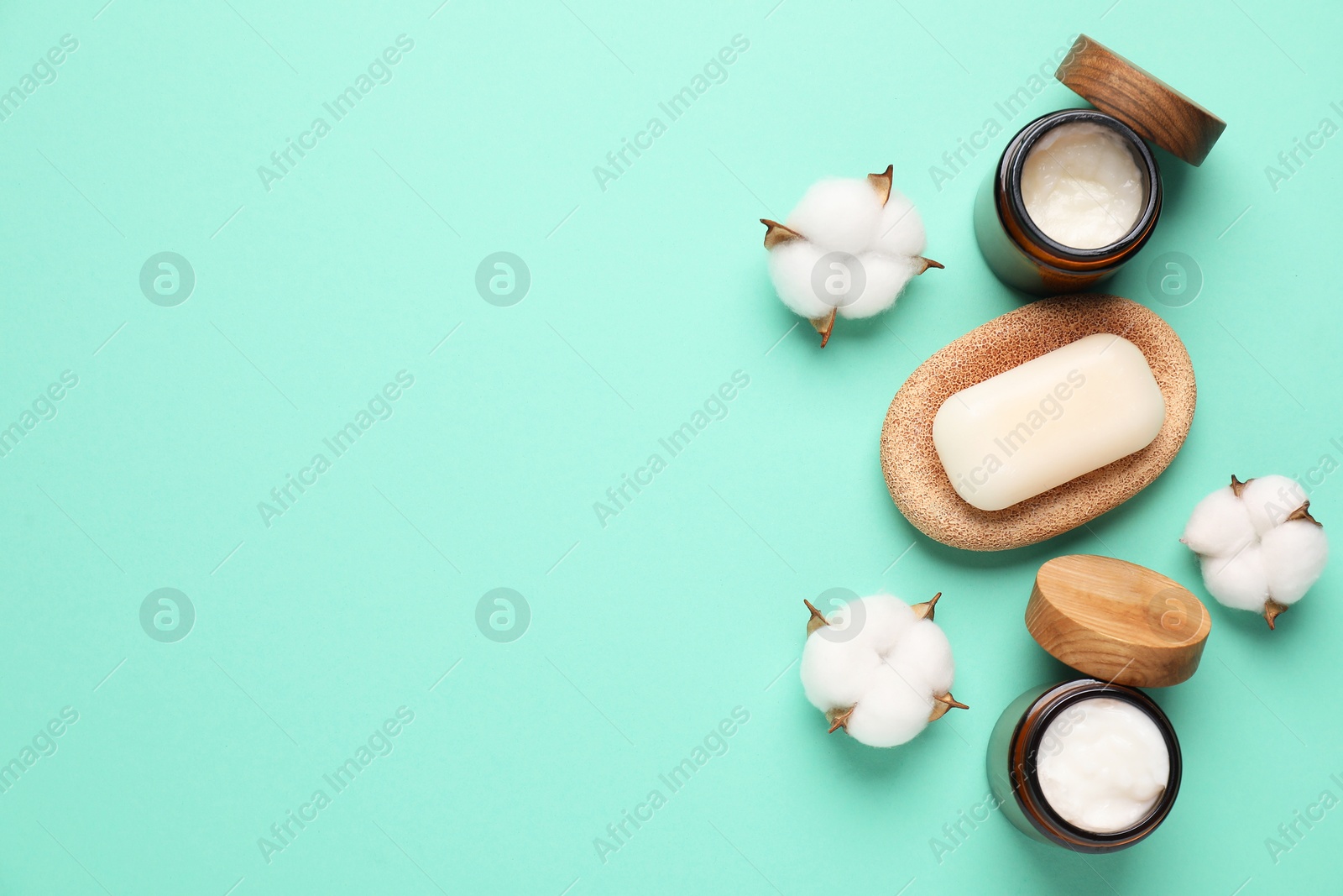 Photo of Different cosmetic products and cotton flowers on turquoise background, flat lay. Space for text