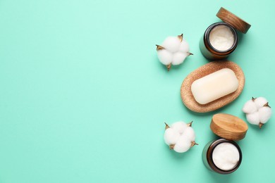 Photo of Different cosmetic products and cotton flowers on turquoise background, flat lay. Space for text