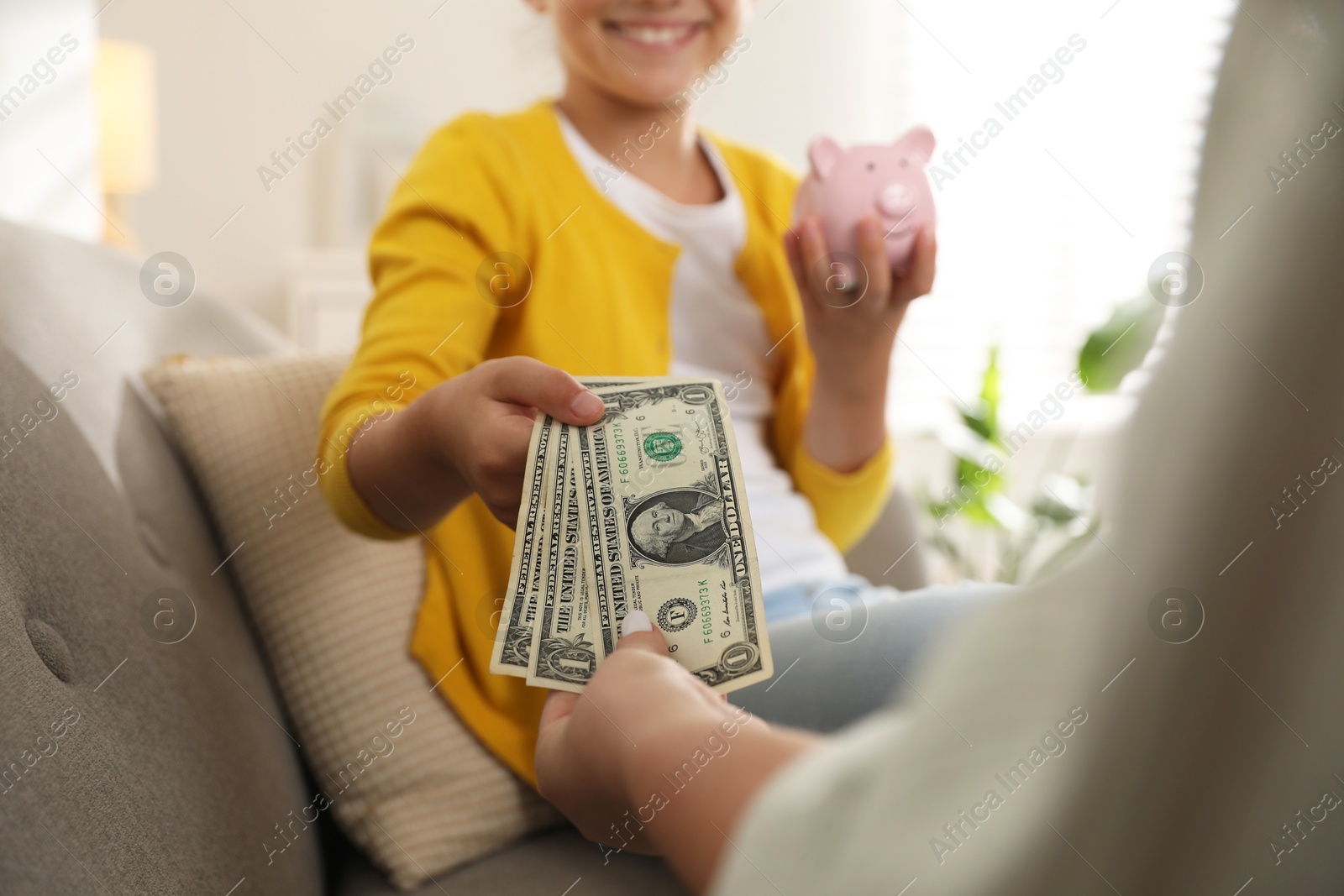 Photo of Mother giving pocket money to her daughter at home, closeup