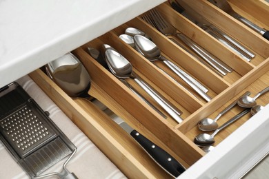 Photo of Box with cutlery in drawer, closeup. Kitchen utensils storage