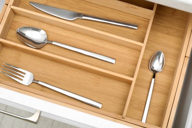 Photo of Box with cutlery in drawer, above view. Kitchen utensils storage