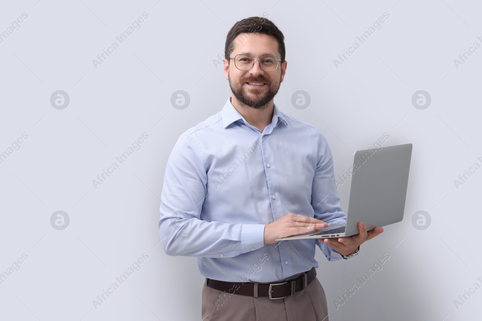 Photo of Portrait of smiling businessman with laptop on grey background