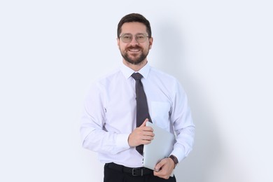 Portrait of smiling businessman with laptop on white background