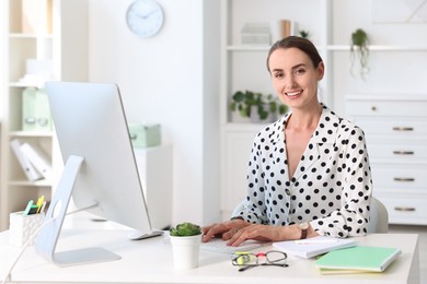 Photo of Smiling businesswoman working at table in office