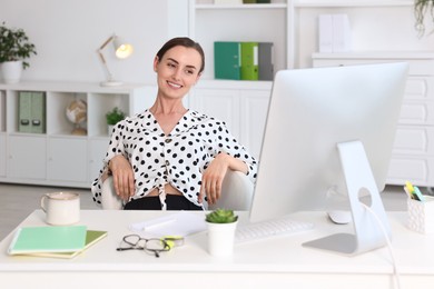 Photo of Smiling businesswoman relaxing at workplace. Break time