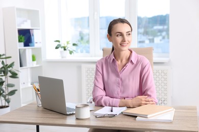 Photo of Smiling businesswoman sitting at table in office