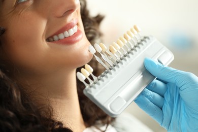 Doctor checking young woman's teeth color in clinic, closeup. Dental veneers