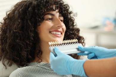 Photo of Doctor checking young woman's teeth color in clinic, closeup. Dental veneers