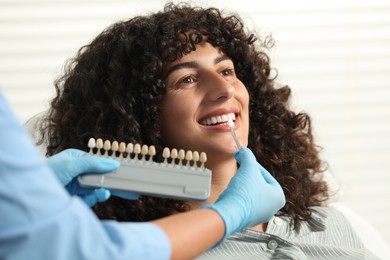 Doctor checking young woman's teeth color in clinic, closeup. Dental veneers