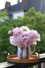 Photo of Beautiful pink peony flowers in vase on balcony railing outdoors