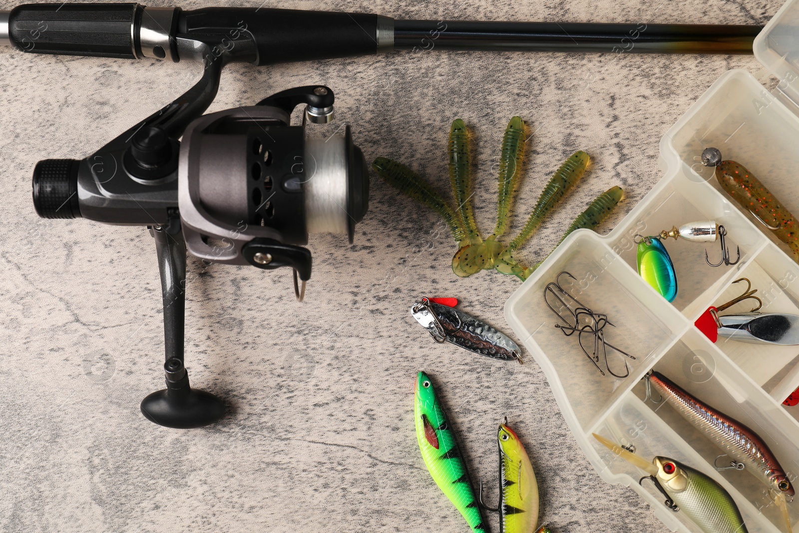 Photo of Fishing baits, hooks and rod with spinning reel on grey table, above view