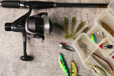 Fishing baits, hooks and rod with spinning reel on grey table, above view