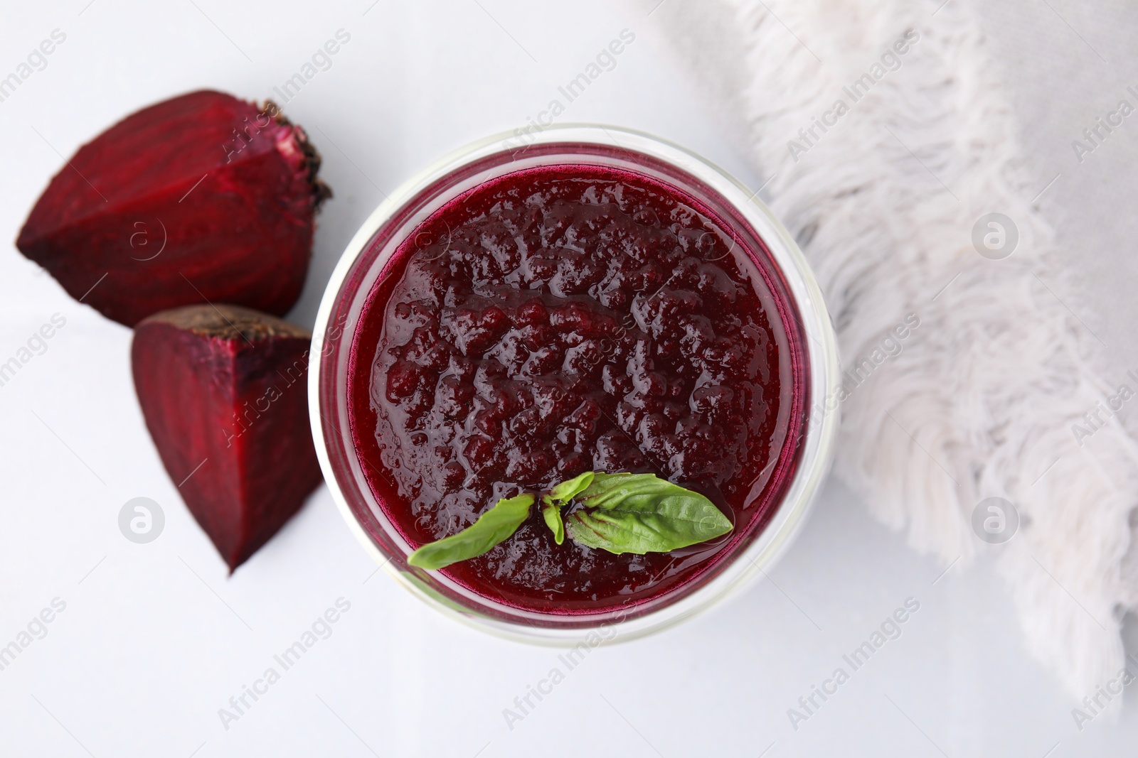 Photo of Fresh beetroot smoothie with mint in glass on white tiled table, top view. Vegan drink