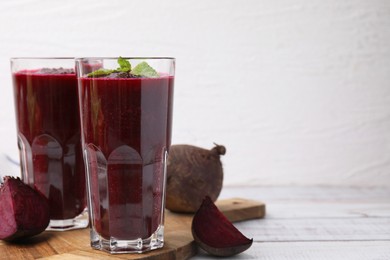 Photo of Fresh beetroot smoothie in glasses on white wooden table, closeup. Space for text