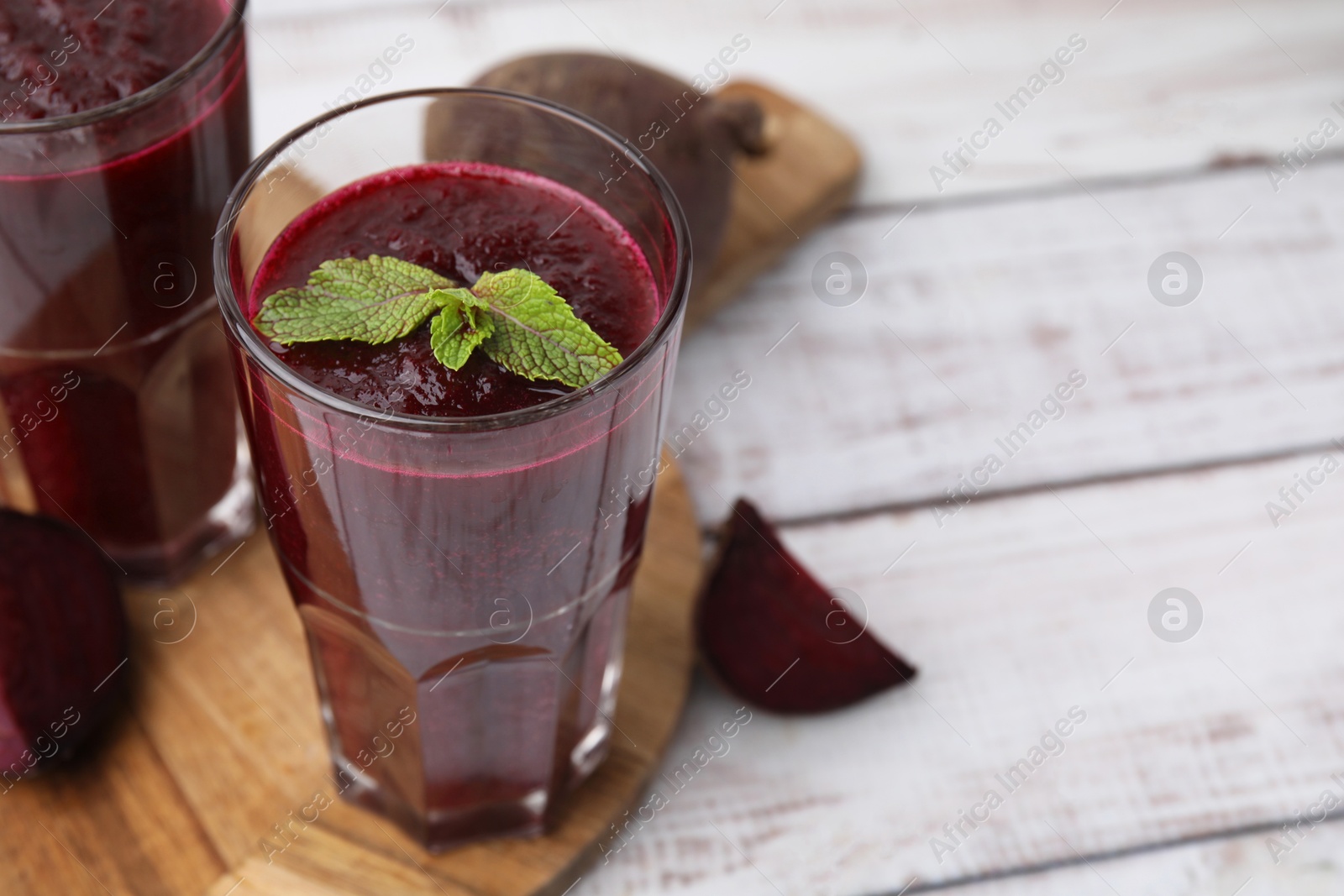 Photo of Fresh beetroot smoothie in glasses on white wooden table, closeup. Space for text