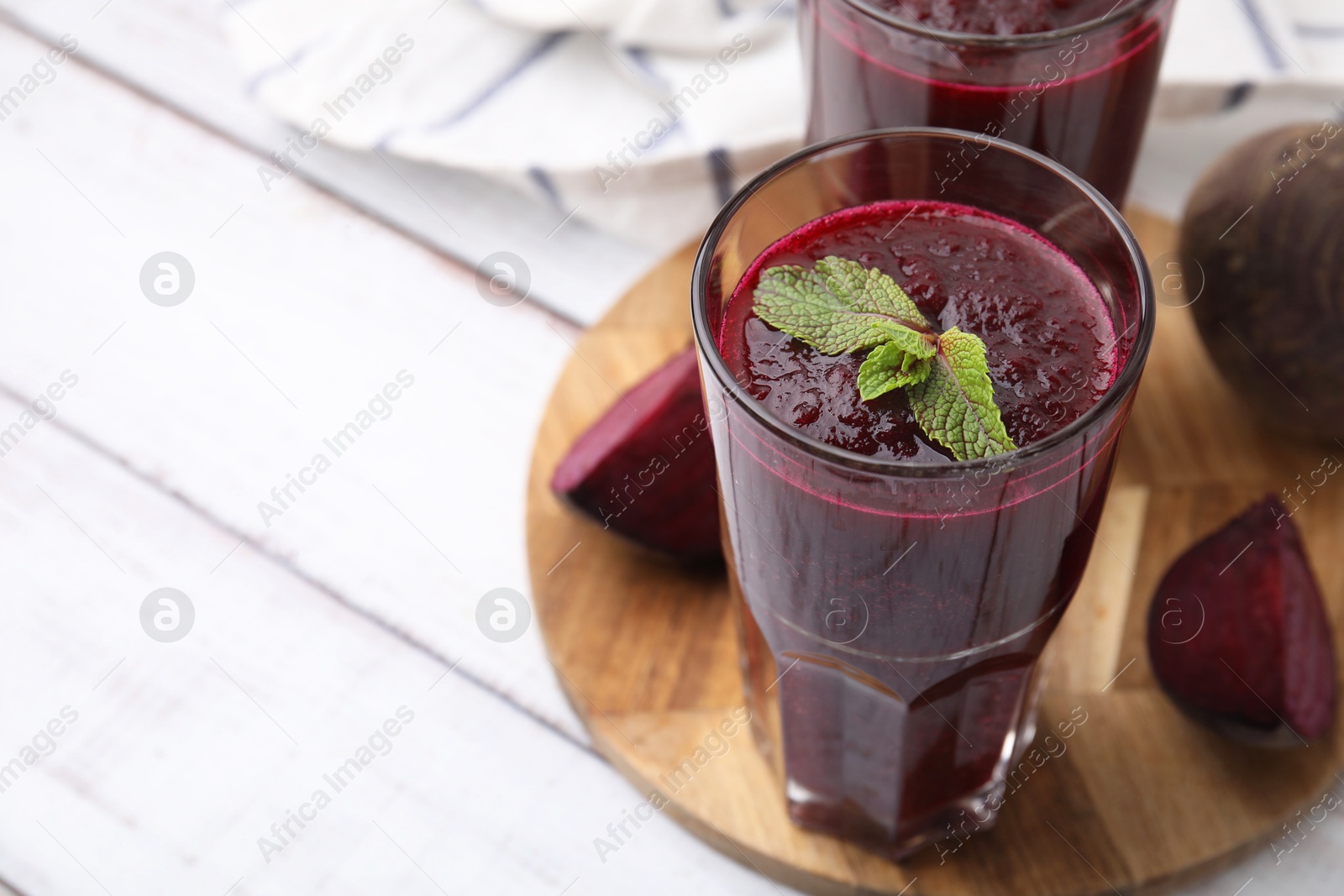 Photo of Fresh beetroot smoothie in glasses on white wooden table, closeup. Space for text