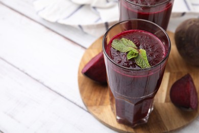 Photo of Fresh beetroot smoothie in glasses on white wooden table, closeup. Space for text