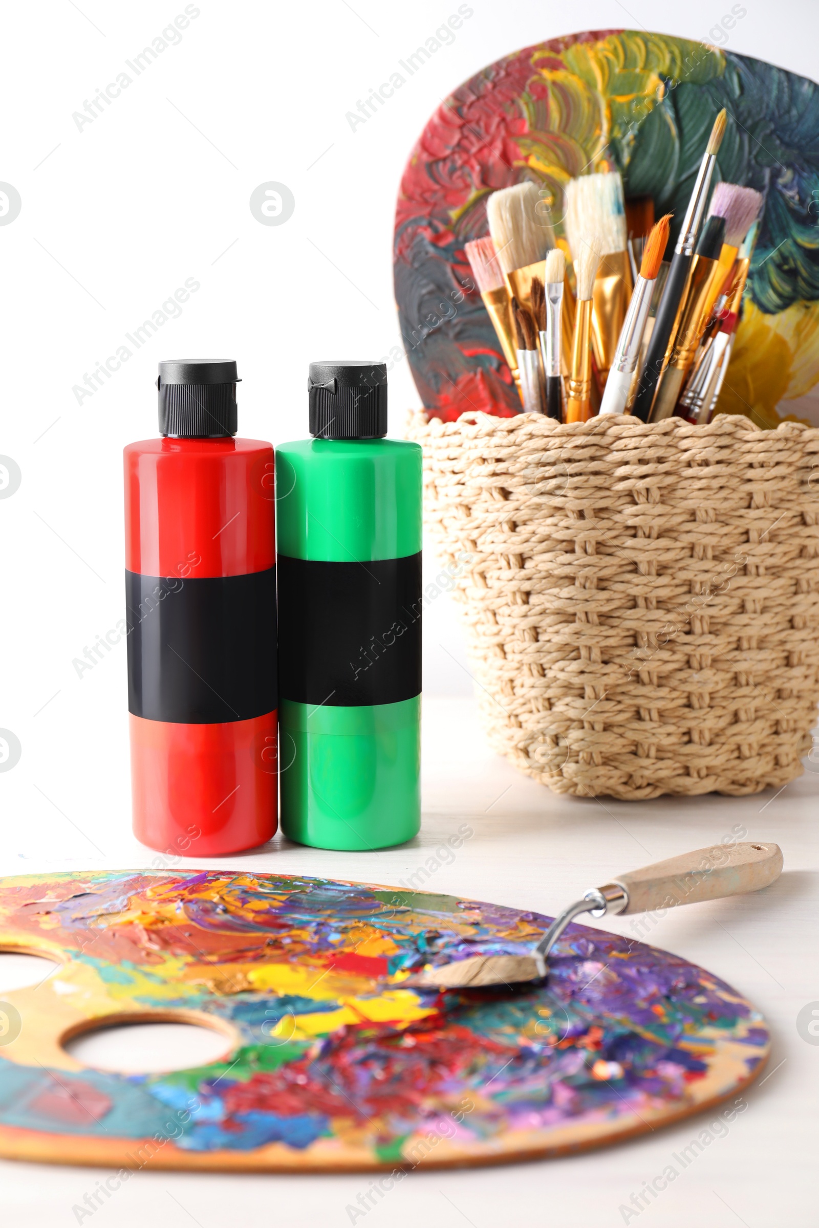 Photo of Acrylic paints of different colors, palettes, knife and brushes on wooden table