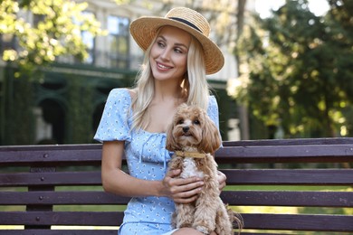 Photo of Beautiful young woman with cute dog on bench in park